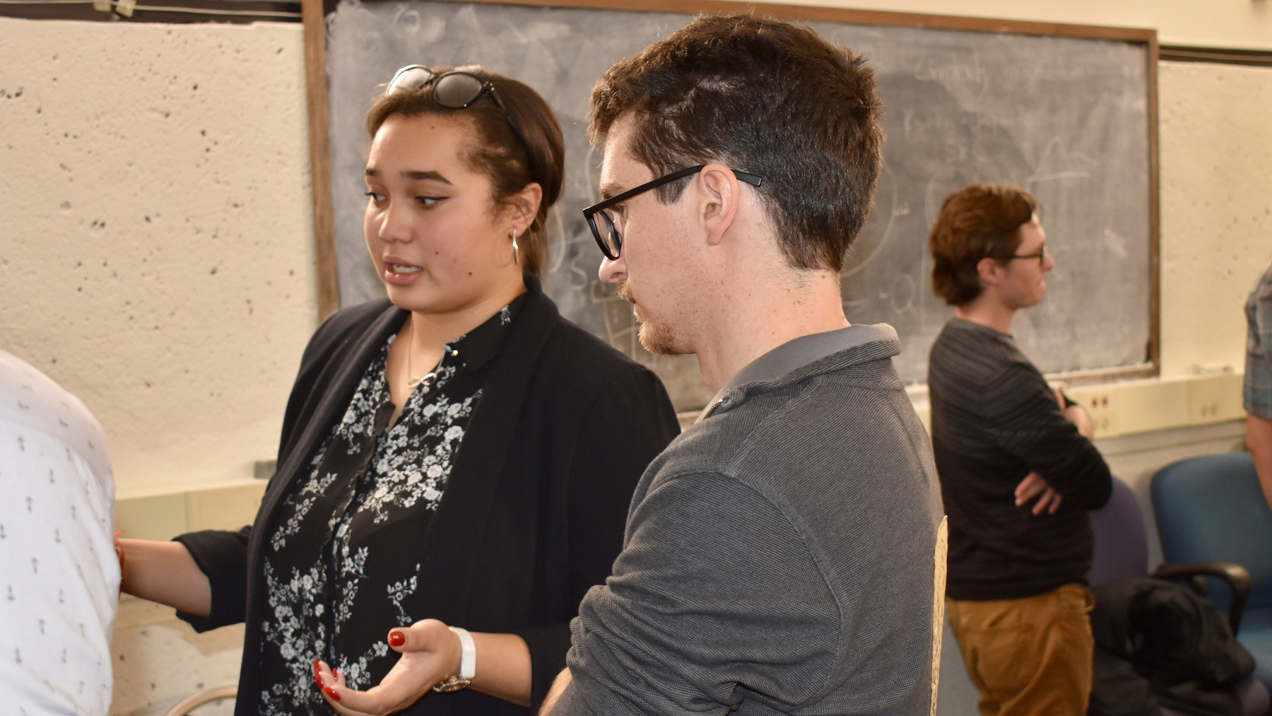 Linguistics major Inna Llanos, in profile, talking with PhD student Adam Liter about her research project